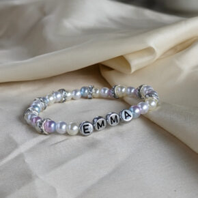 Namensarmband mit weißen und roséfarbenen Perlen. Die Zwischenringe sind silbern und mit Strasssteinen besetzt. Die Buchstaben sind schwarz auf silbernen Perlen