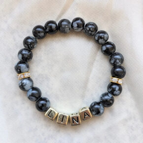 Namensarmband mit schwarz marmorierten Perlen. Die Zwischenringe sind goldfarben und Strasssteinen besetzt. Die Buchstaben sind schwarz auf goldfarbenen Perlen