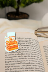 Magnetisches Lesezeichen mit Aquarellmotiv Teetasse und Bücherstapel.